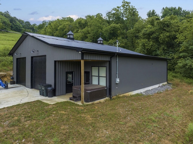 exterior space featuring a lawn, a garage, and an outbuilding