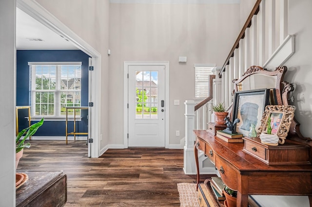 entryway featuring a towering ceiling and dark wood-type flooring