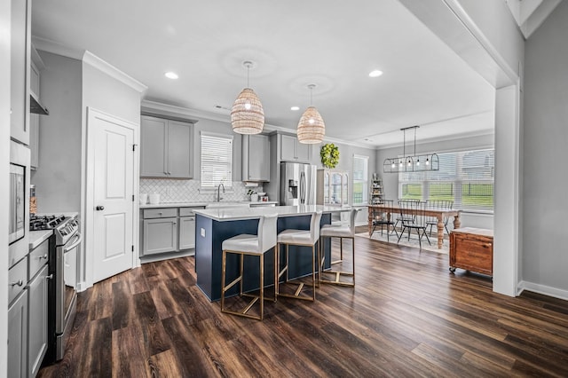 kitchen with gray cabinets, a center island, stainless steel appliances, and decorative light fixtures