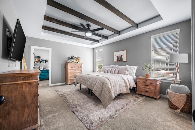 carpeted bedroom with a raised ceiling, ceiling fan, and beamed ceiling