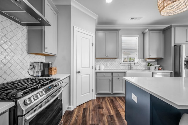 kitchen featuring gray cabinetry, sink, wall chimney exhaust hood, ornamental molding, and stainless steel appliances