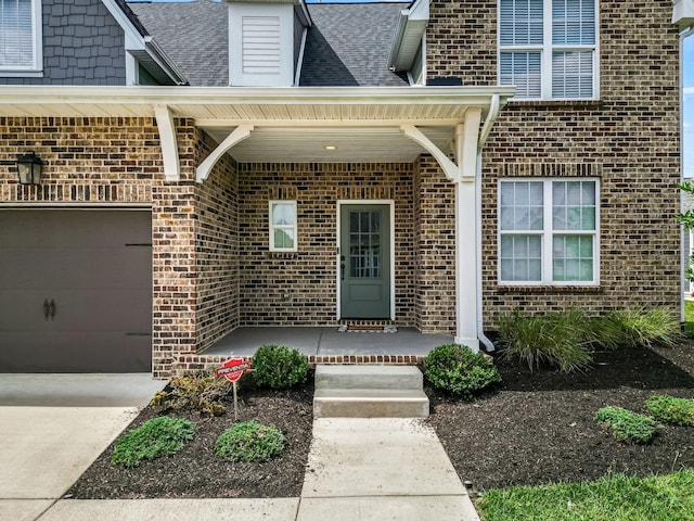 view of exterior entry featuring a porch and a garage