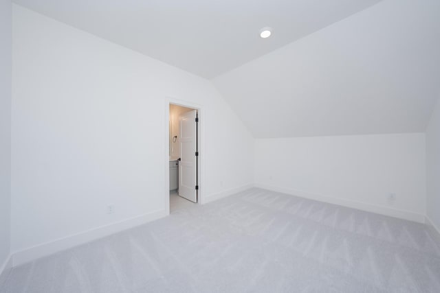 additional living space with light colored carpet and vaulted ceiling