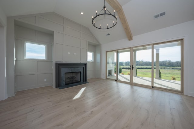 unfurnished living room with beamed ceiling, an inviting chandelier, high vaulted ceiling, and light hardwood / wood-style floors