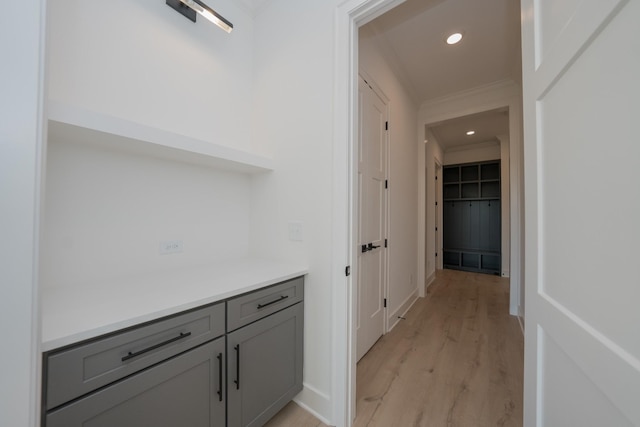 corridor featuring light wood-type flooring and ornamental molding