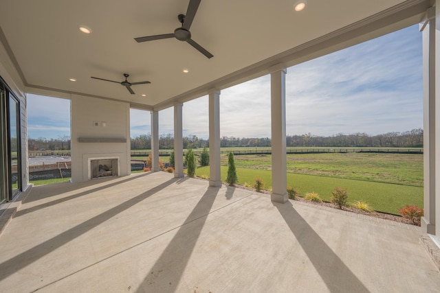 view of patio featuring ceiling fan, a fireplace, and a rural view