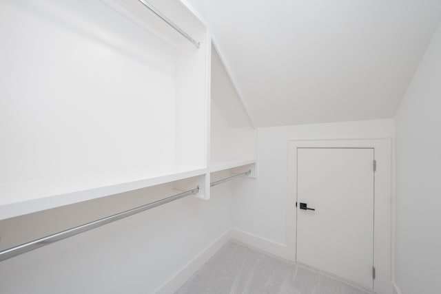 spacious closet with light colored carpet and vaulted ceiling