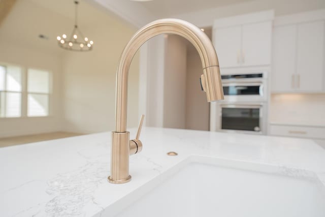 details with white cabinetry, hanging light fixtures, double wall oven, and light stone counters