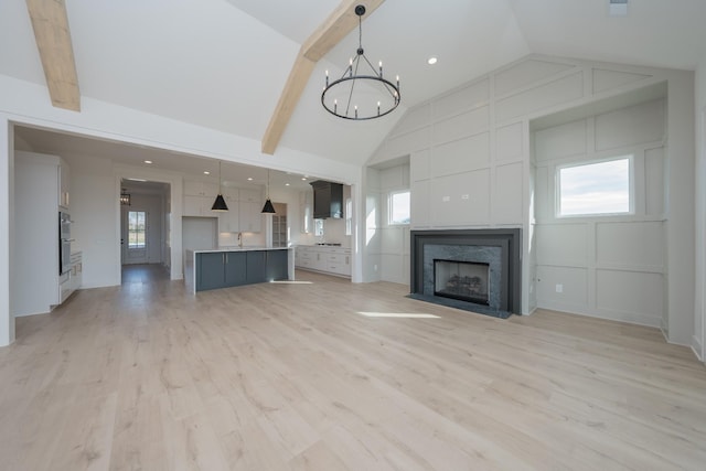 unfurnished living room with beamed ceiling, light wood-type flooring, a fireplace, and a wealth of natural light