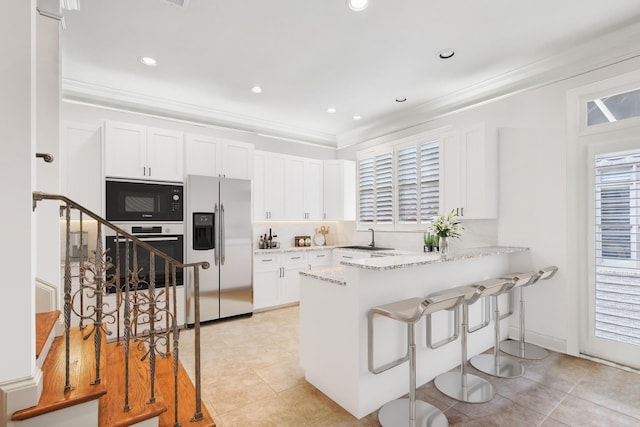 kitchen featuring black microwave, light stone countertops, white cabinets, stainless steel refrigerator with ice dispenser, and light tile patterned floors