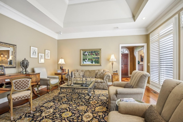 living room featuring wood-type flooring, a tray ceiling, and ornamental molding