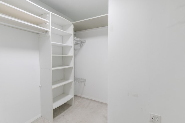 walk in closet with light colored carpet