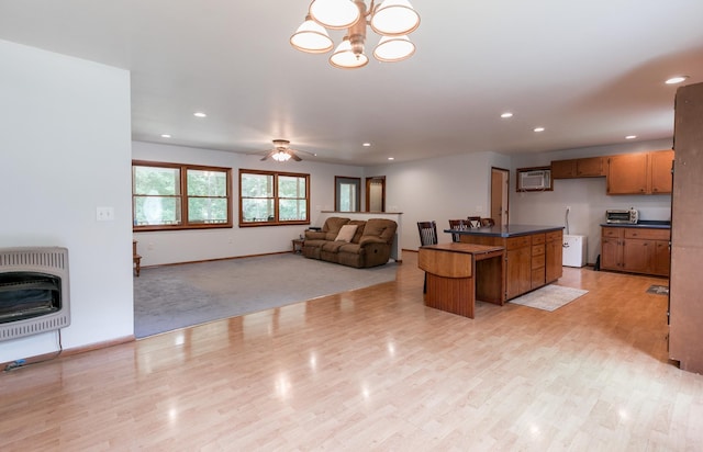 kitchen with a center island, ceiling fan with notable chandelier, heating unit, and light hardwood / wood-style floors