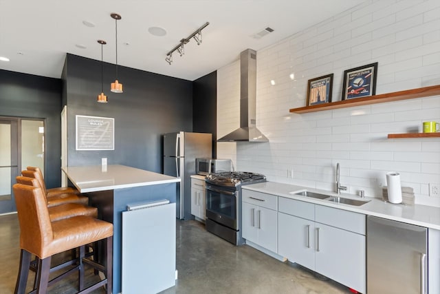 kitchen featuring pendant lighting, a breakfast bar, wall chimney range hood, sink, and appliances with stainless steel finishes