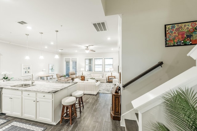 kitchen featuring light stone counters, ceiling fan, dark wood-type flooring, sink, and white cabinets