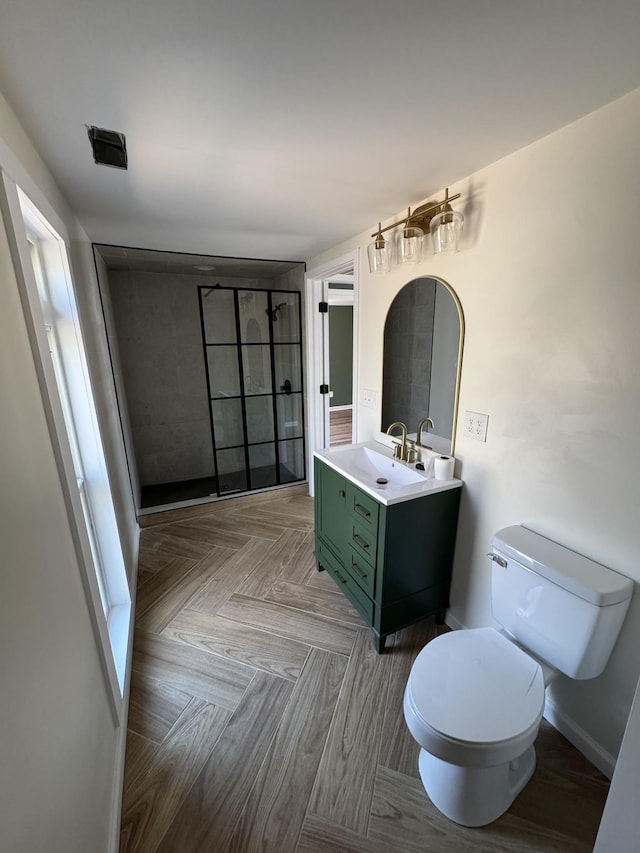 full bath featuring baseboards, toilet, vanity, and a tile shower