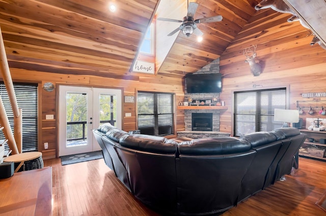 living room with lofted ceiling, wood walls, wood ceiling, and ceiling fan