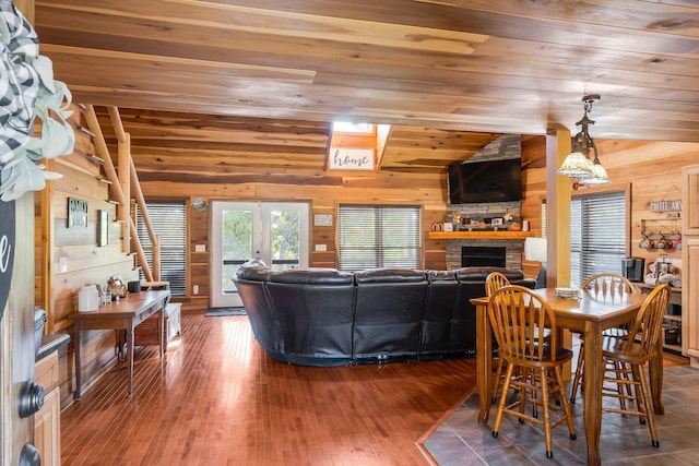 living room featuring a fireplace, lofted ceiling, wood walls, and wood ceiling