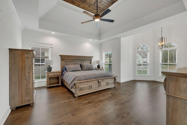 bedroom featuring dark wood-type flooring, ceiling fan with notable chandelier, a tray ceiling, and wooden ceiling