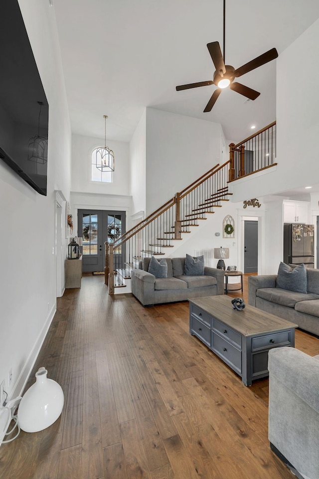 living room with dark hardwood / wood-style flooring, ceiling fan, french doors, and a towering ceiling