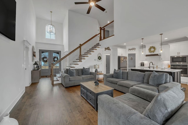 living room featuring ceiling fan, french doors, sink, dark wood-type flooring, and a towering ceiling