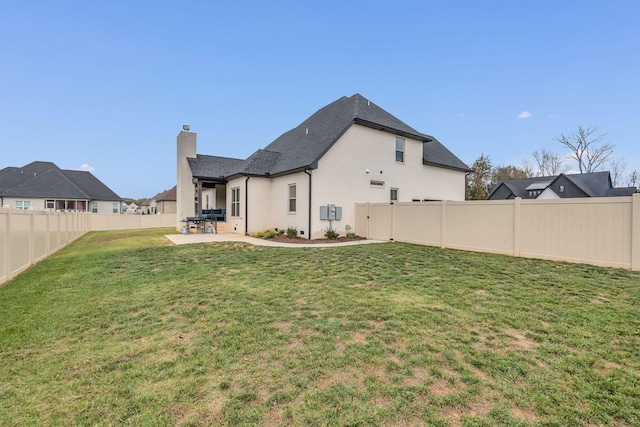 rear view of property with a lawn and a patio