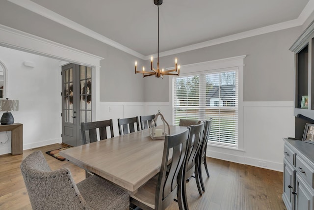 dining room with light hardwood / wood-style flooring, an inviting chandelier, and crown molding