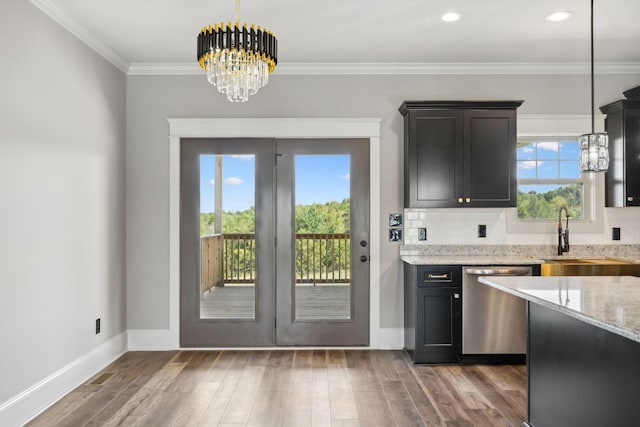 kitchen featuring an inviting chandelier, light stone counters, stainless steel dishwasher, crown molding, and decorative light fixtures