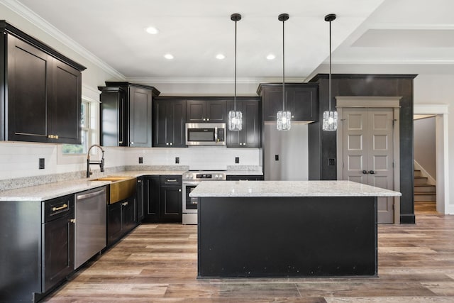 kitchen featuring pendant lighting, a center island, sink, light hardwood / wood-style floors, and stainless steel appliances