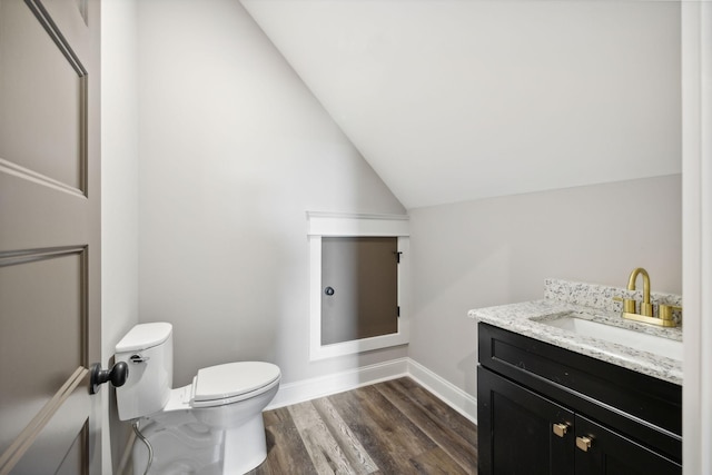 bathroom featuring wood-type flooring, vanity, toilet, and lofted ceiling