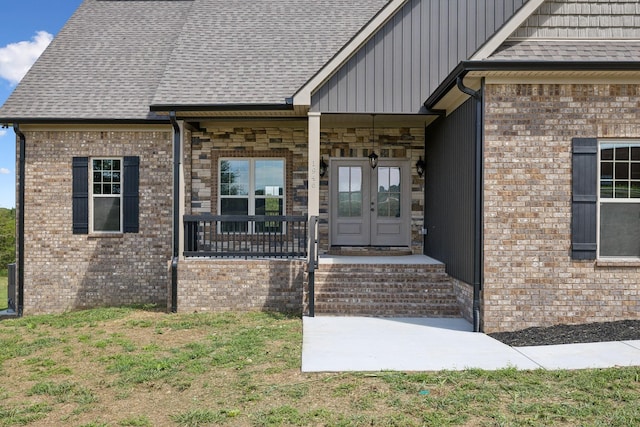 entrance to property with a yard, french doors, and a porch