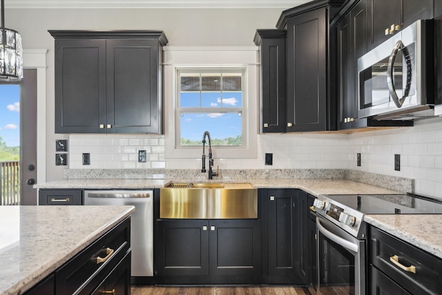 kitchen featuring dark wood-type flooring, crown molding, sink, hanging light fixtures, and appliances with stainless steel finishes