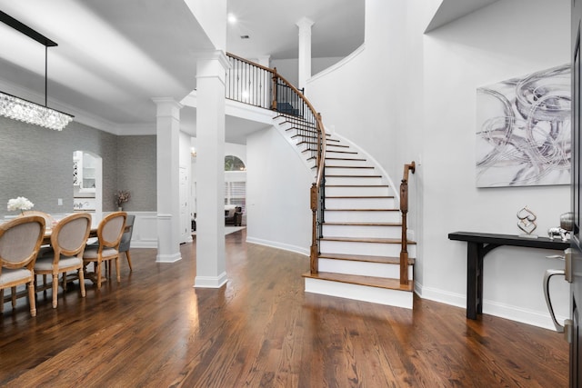 interior space featuring ornamental molding, an inviting chandelier, ornate columns, and dark wood-type flooring