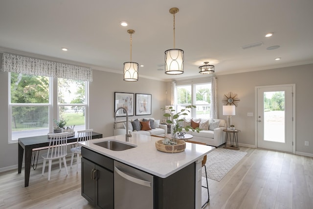 kitchen featuring pendant lighting, sink, crown molding, dishwasher, and a center island with sink