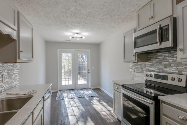 kitchen with gray cabinetry, french doors, tasteful backsplash, dark hardwood / wood-style flooring, and appliances with stainless steel finishes