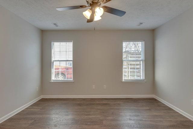 spare room featuring a wealth of natural light, dark wood-type flooring, and ceiling fan