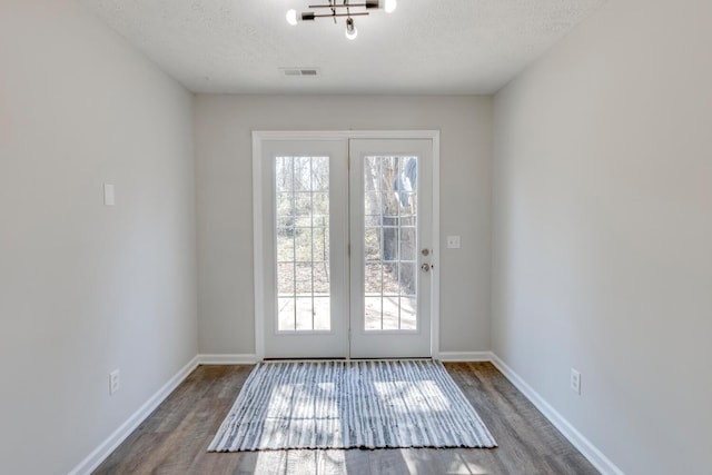 entryway with a textured ceiling, hardwood / wood-style flooring, and an inviting chandelier