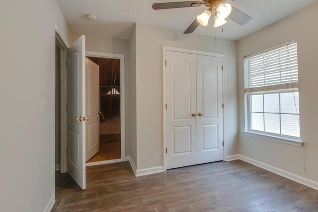 unfurnished bedroom featuring hardwood / wood-style floors, ceiling fan, multiple windows, and a closet