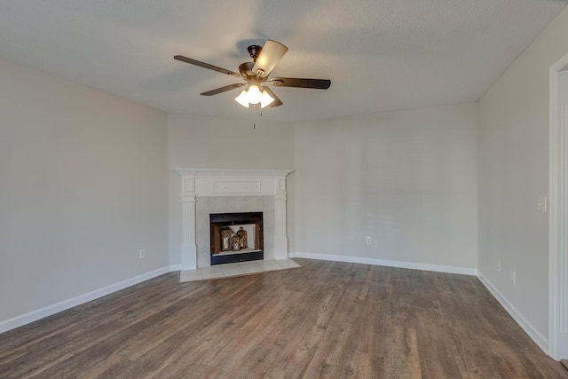 unfurnished living room featuring a tile fireplace, wood-type flooring, a textured ceiling, and ceiling fan