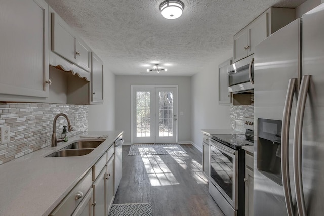 kitchen with sink, french doors, stainless steel appliances, decorative backsplash, and hardwood / wood-style flooring