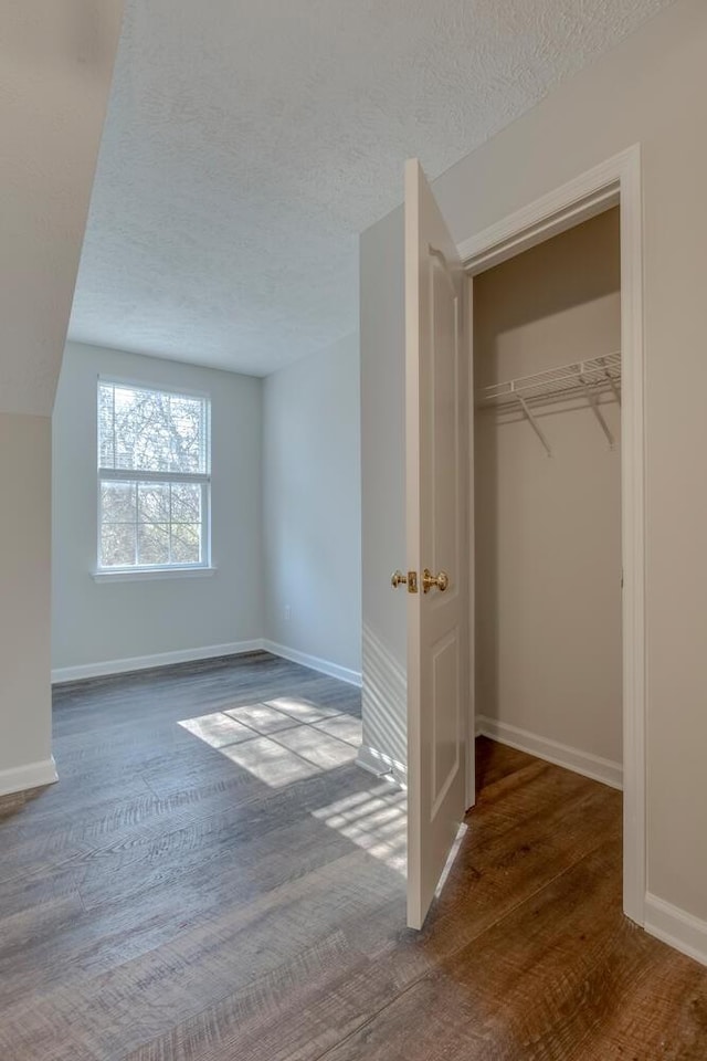 unfurnished bedroom with a closet, wood-type flooring, and a textured ceiling