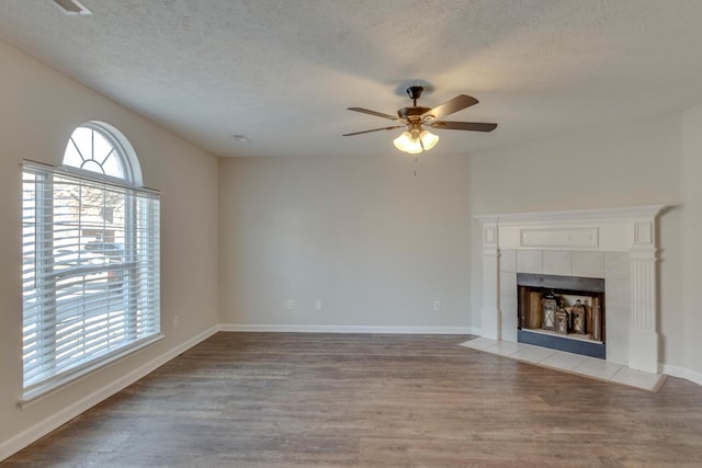 unfurnished living room with a textured ceiling, ceiling fan, light wood-type flooring, and a fireplace