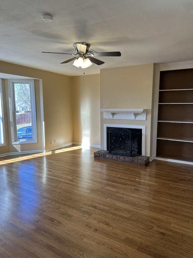 unfurnished living room with ceiling fan, built in features, and dark wood-type flooring