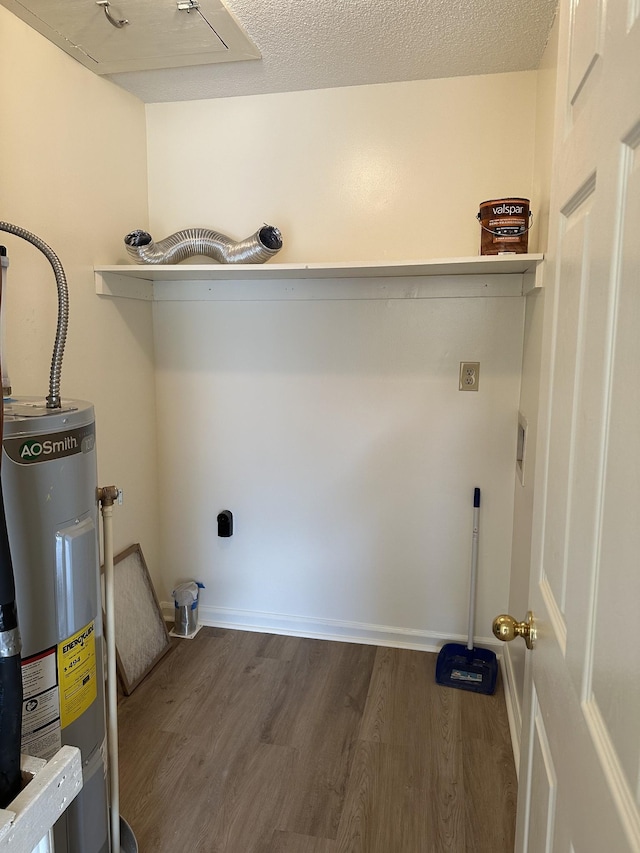 laundry area with hookup for an electric dryer, dark hardwood / wood-style flooring, electric water heater, and a textured ceiling