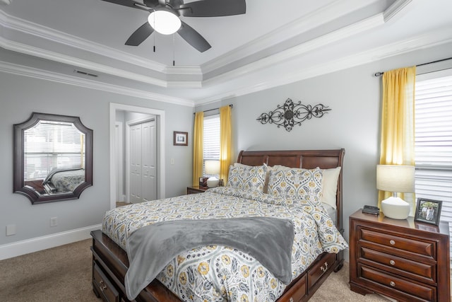 carpeted bedroom featuring ceiling fan, ornamental molding, a tray ceiling, and a closet