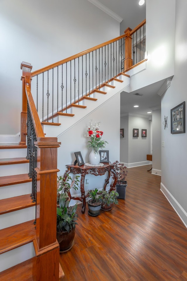 stairway with wood-type flooring and ornamental molding