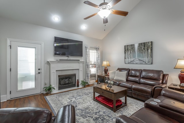 living room featuring a tiled fireplace, ceiling fan, hardwood / wood-style floors, and high vaulted ceiling