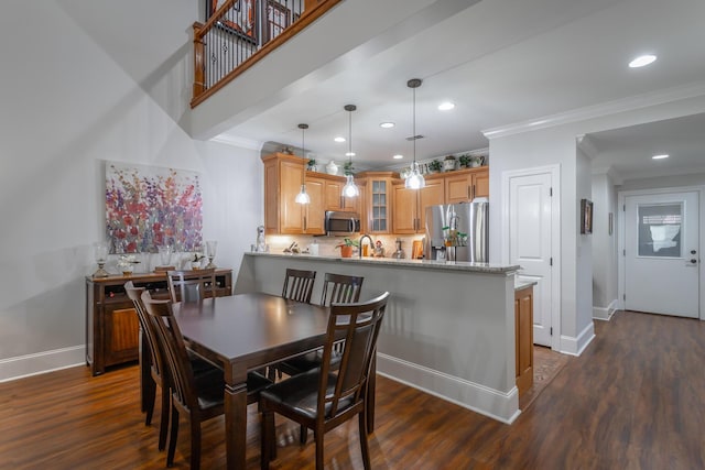 dining area featuring sink, crown molding, and dark wood-type flooring