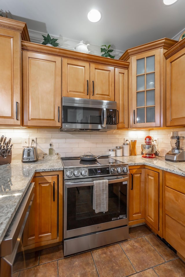 kitchen with light stone countertops, backsplash, and stainless steel appliances