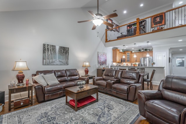 living room with ceiling fan, hardwood / wood-style floors, high vaulted ceiling, and ornamental molding